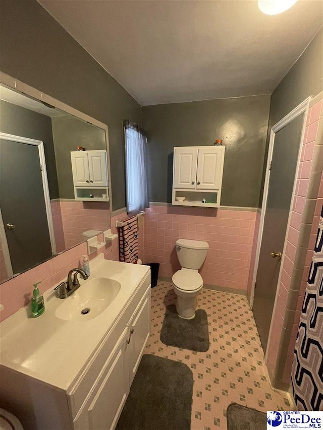 bathroom with vanity, tile walls, and toilet