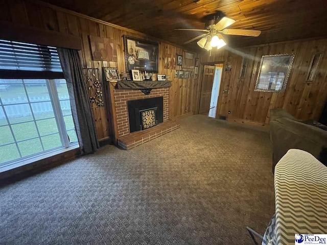 carpeted living room featuring a brick fireplace, wood ceiling, ceiling fan, and wood walls