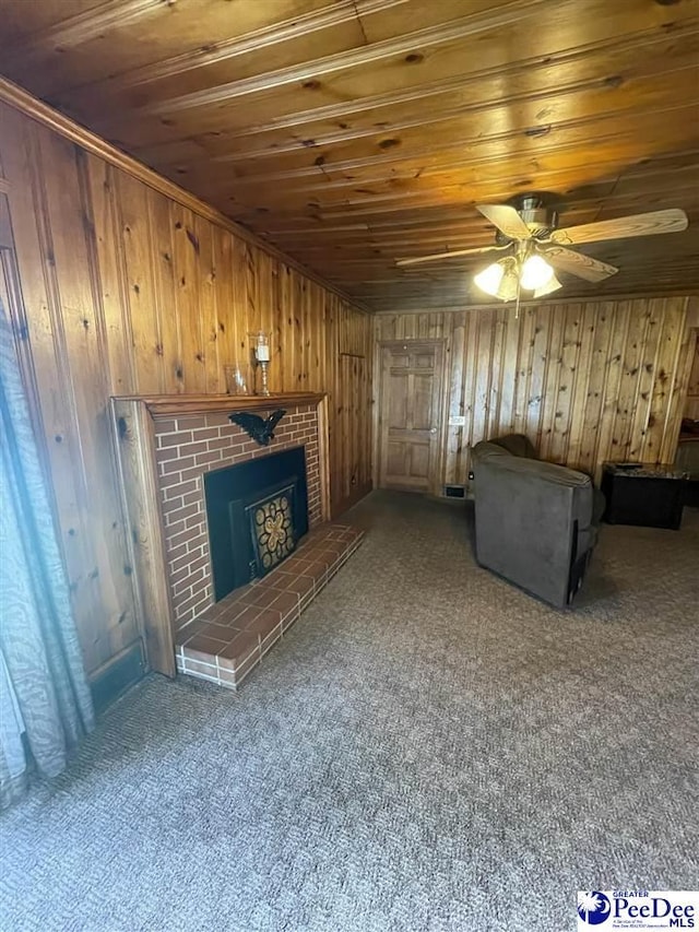 unfurnished living room with carpet flooring, wooden ceiling, a fireplace, and wood walls