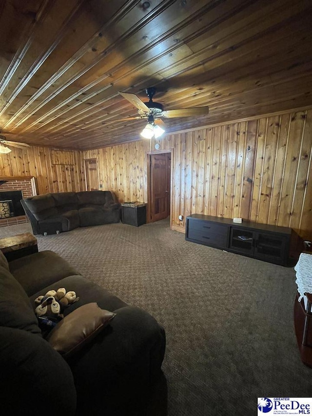 carpeted cinema room featuring ceiling fan, a fireplace, wood walls, and wooden ceiling