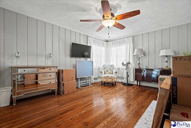 living area featuring a textured ceiling, ornamental molding, wood finished floors, and a ceiling fan