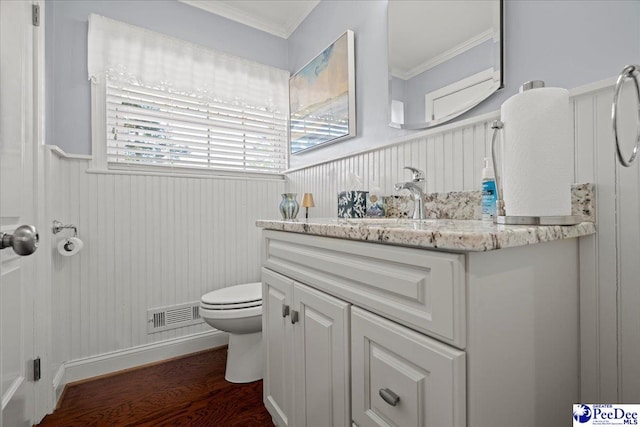 bathroom with visible vents, toilet, ornamental molding, wood finished floors, and vanity