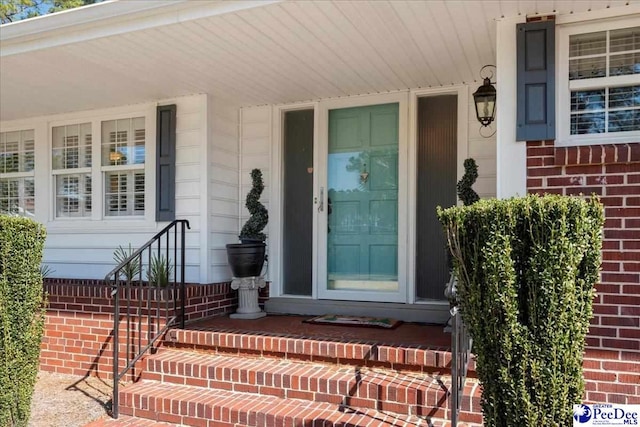 entrance to property with brick siding and a porch