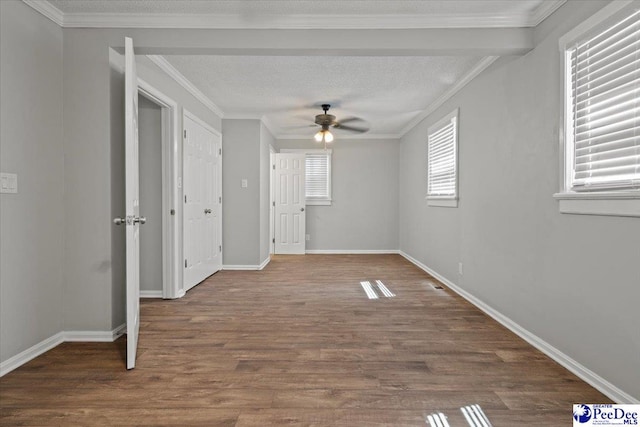 interior space with baseboards, a textured ceiling, crown molding, and wood finished floors