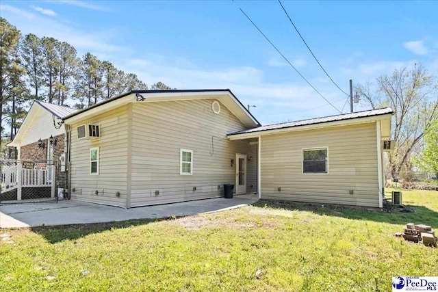 rear view of property with a standing seam roof, a patio area, cooling unit, metal roof, and a yard