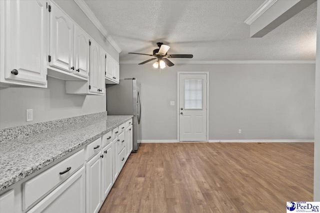 kitchen featuring crown molding, ceiling fan, white cabinets, and freestanding refrigerator