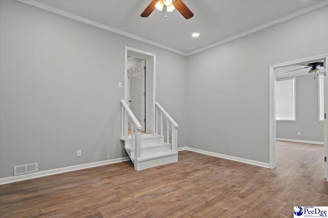 empty room featuring crown molding, visible vents, wood finished floors, and a ceiling fan
