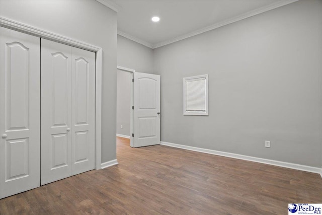 unfurnished bedroom featuring baseboards, a closet, crown molding, and wood finished floors