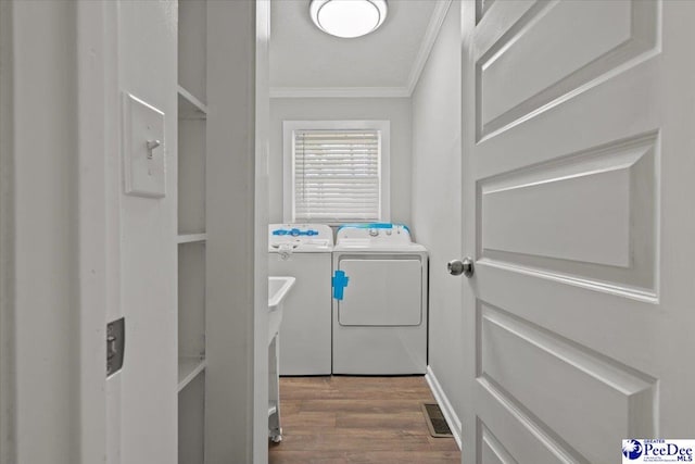 laundry room featuring washer and clothes dryer, crown molding, visible vents, laundry area, and wood finished floors