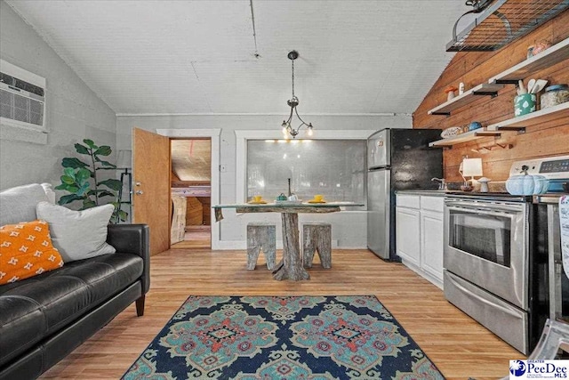 interior space with pendant lighting, appliances with stainless steel finishes, vaulted ceiling, and light wood-type flooring