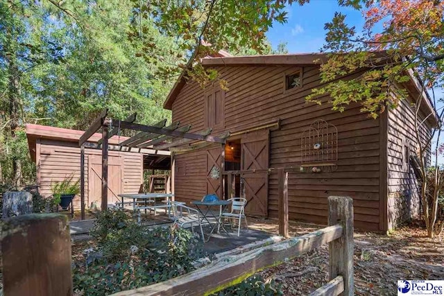 rear view of house with an outdoor structure and a pergola