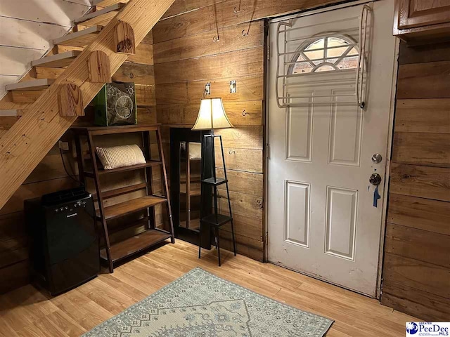 foyer entrance featuring light wood-type flooring and wood walls