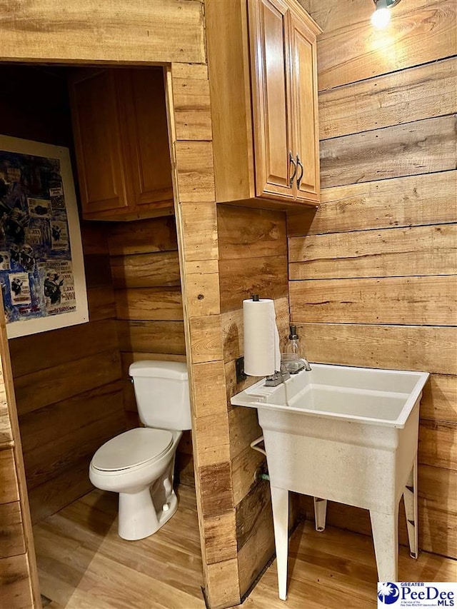 bathroom with hardwood / wood-style flooring, wooden walls, and toilet