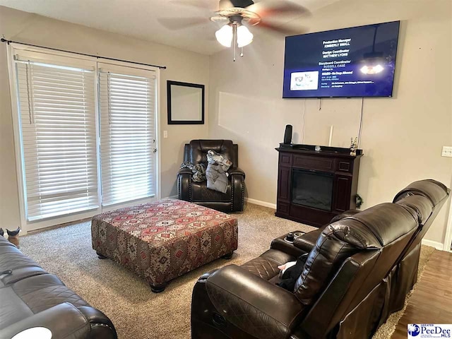 living area featuring baseboards, ceiling fan, and a healthy amount of sunlight