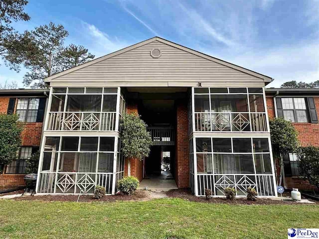 back of property featuring a sunroom and brick siding