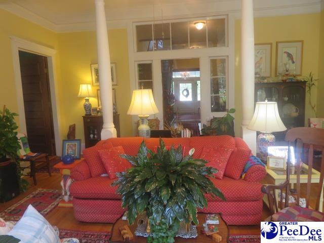 living room with ornamental molding and ornate columns