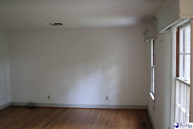 unfurnished room with baseboards and wood finished floors