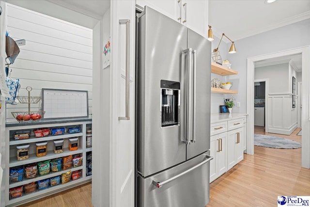 kitchen with white cabinetry, high end refrigerator, crown molding, and light hardwood / wood-style flooring