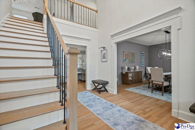 entrance foyer with an inviting chandelier, hardwood / wood-style floors, and a towering ceiling