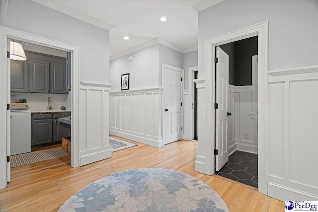 bathroom with sink, washer / dryer, wood-type flooring, and ornamental molding