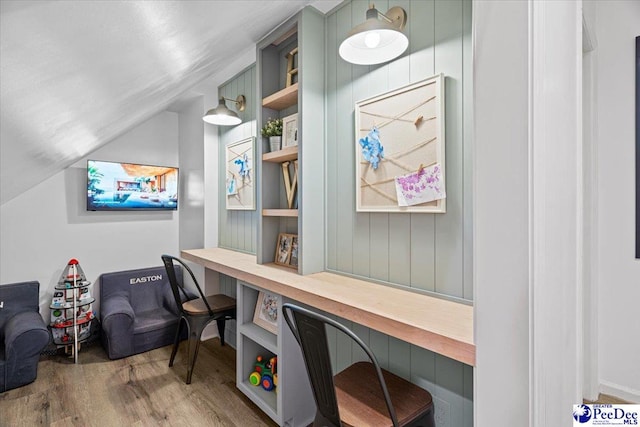 office featuring vaulted ceiling, built in desk, and light hardwood / wood-style floors