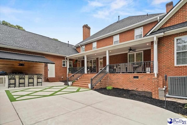 back of property with cooling unit, ceiling fan, an outdoor bar, and a patio