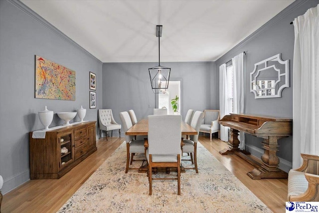 dining space with crown molding and light wood-type flooring