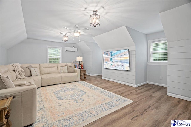 living room with a healthy amount of sunlight, wood-type flooring, lofted ceiling, and an AC wall unit