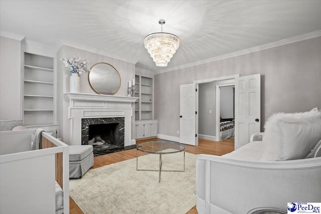 living room featuring wood-type flooring, crown molding, built in features, and a fireplace