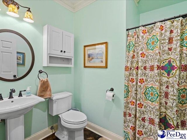 bathroom featuring baseboards, a shower with shower curtain, toilet, and crown molding