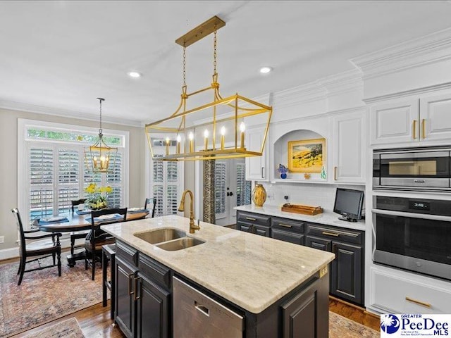 kitchen featuring ornamental molding, a kitchen island with sink, stainless steel appliances, white cabinetry, and a sink