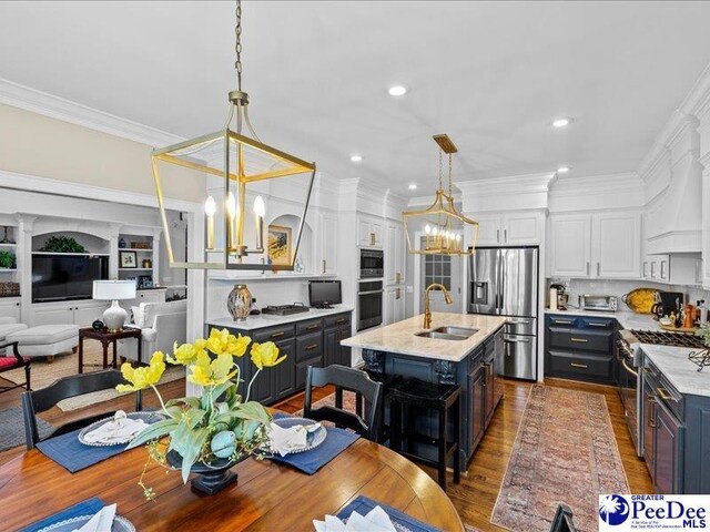 kitchen featuring a sink, white cabinetry, appliances with stainless steel finishes, an inviting chandelier, and crown molding