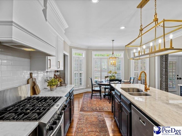 kitchen with stainless steel appliances, a sink, custom range hood, dark wood finished floors, and crown molding