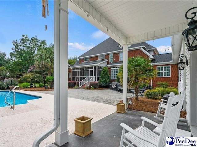 view of patio featuring a sunroom and a fenced in pool