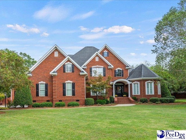 view of front of home with crawl space, brick siding, and a front yard