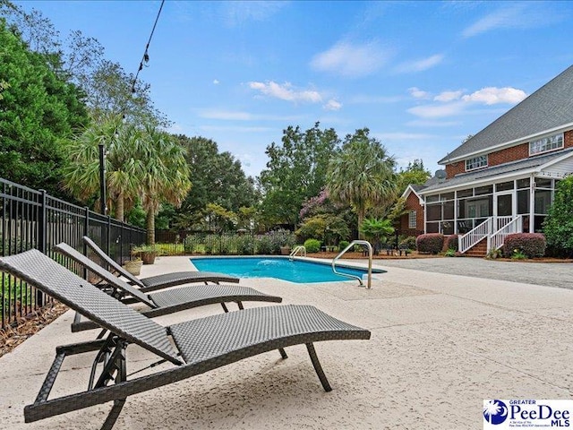 view of swimming pool with a patio area, fence, a sunroom, and a fenced in pool