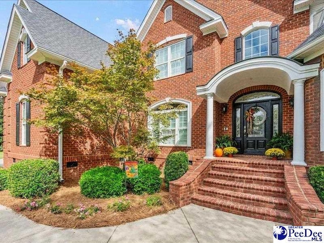 property entrance featuring a shingled roof and brick siding