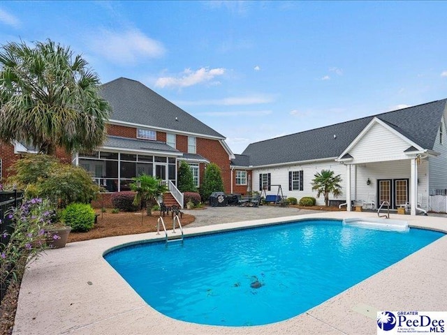 pool with a sunroom, a patio area, and french doors