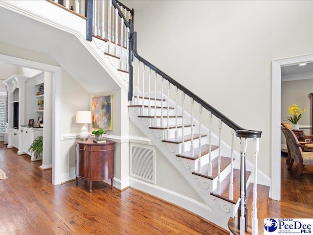 stairway featuring visible vents, a towering ceiling, baseboards, and wood finished floors