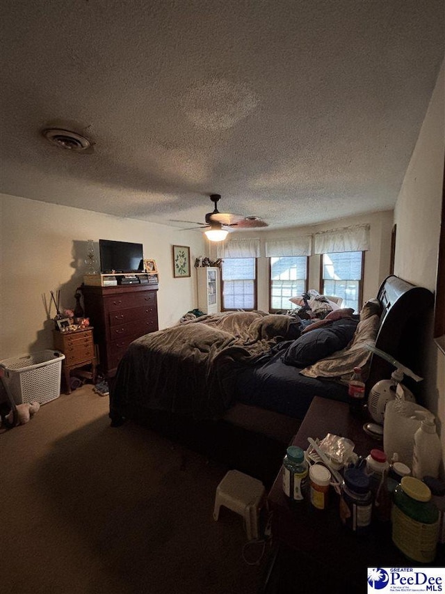 carpeted bedroom with a ceiling fan, visible vents, and a textured ceiling