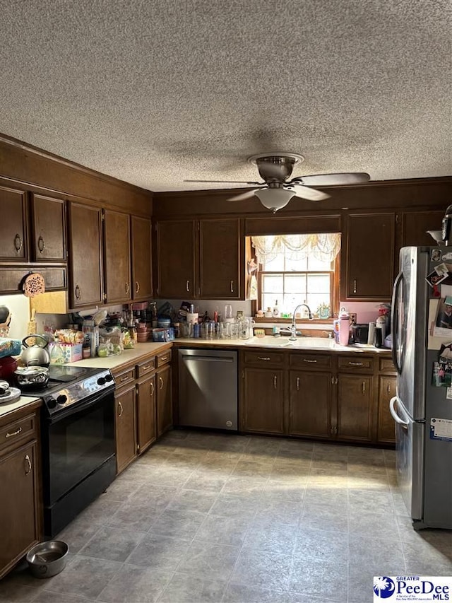 kitchen featuring ceiling fan, a sink, light countertops, dark brown cabinets, and appliances with stainless steel finishes