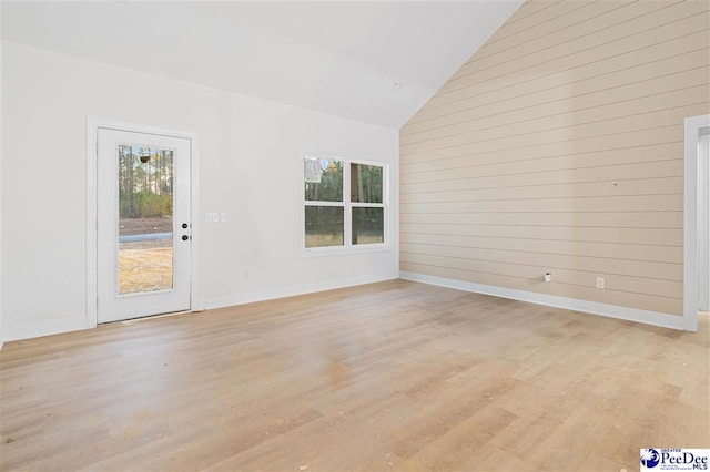 spare room featuring a wealth of natural light, light hardwood / wood-style floors, and wood walls