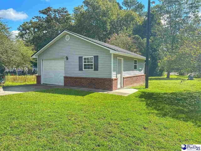 view of side of home featuring a garage, a lawn, and an outdoor structure