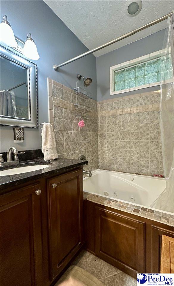 bathroom with tile patterned floors, vanity, shower / bath combo with shower curtain, and a textured ceiling