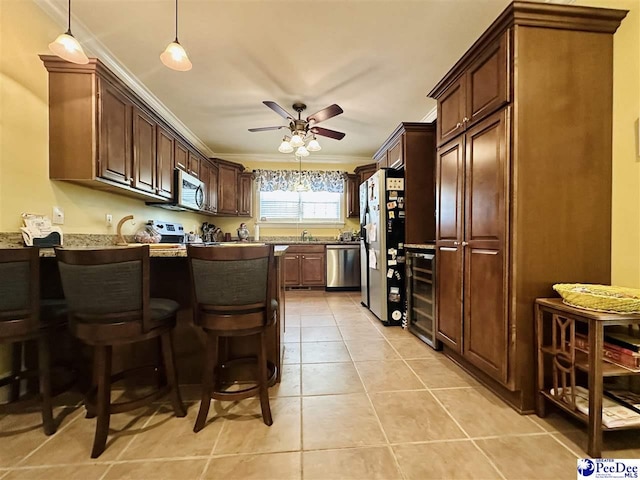 kitchen with crown molding, light tile patterned floors, a kitchen breakfast bar, stainless steel appliances, and beverage cooler