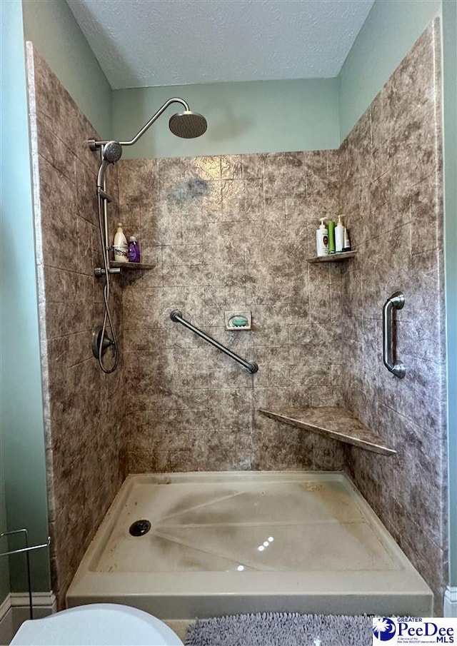 bathroom with tiled shower, toilet, and a textured ceiling