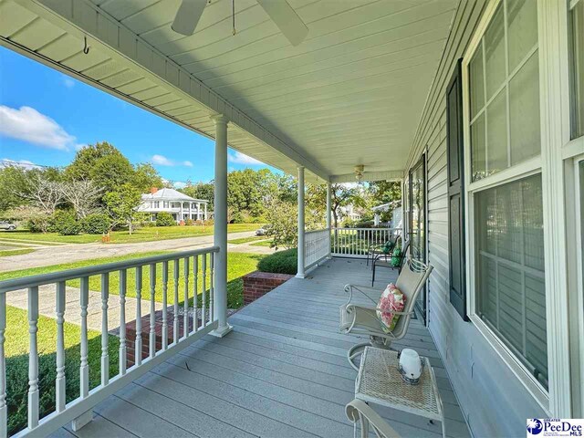 wooden deck featuring a yard, ceiling fan, and covered porch