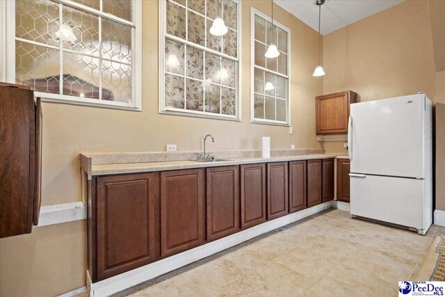 kitchen featuring hanging light fixtures, sink, and white refrigerator