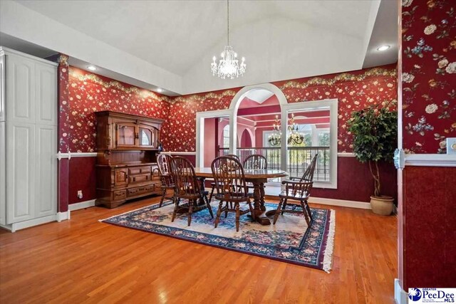 dining space with vaulted ceiling, a notable chandelier, and light wood-type flooring