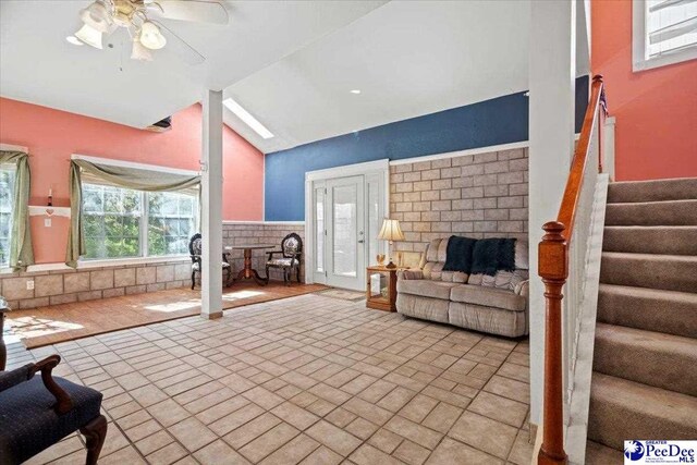 unfurnished living room featuring ceiling fan, vaulted ceiling, and a brick fireplace